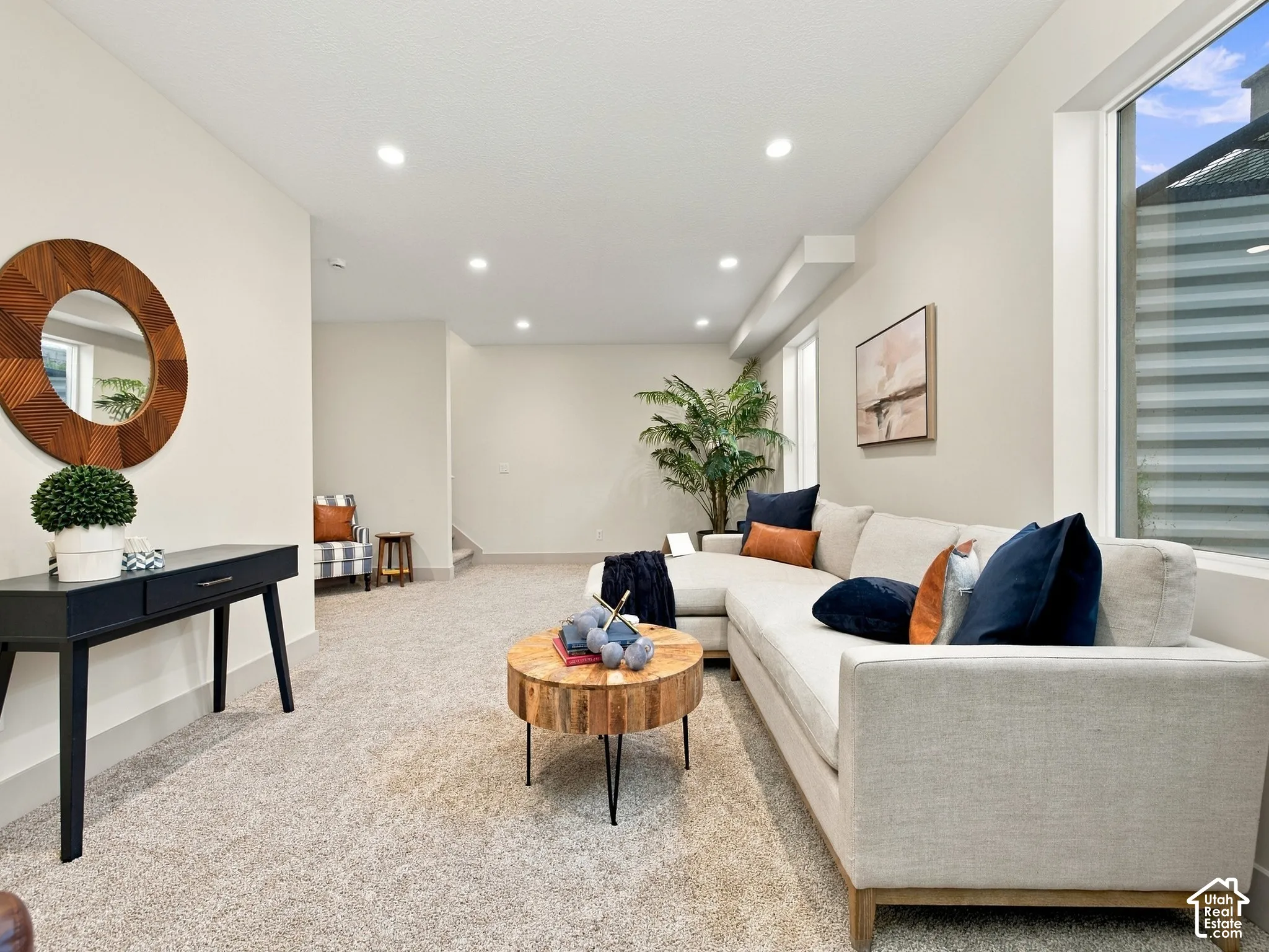 Expansive living space featuring recessed lighting, a large window with privacy blinds, and light-toned carpeting