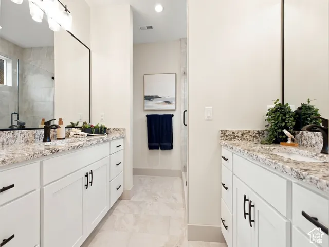Dual vanities with stone countertops, white shaker cabinetry, and matte black hardware