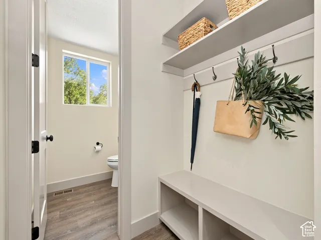 Built-in mudroom bench with shelving, wall-mounted hooks, and overhead shelving