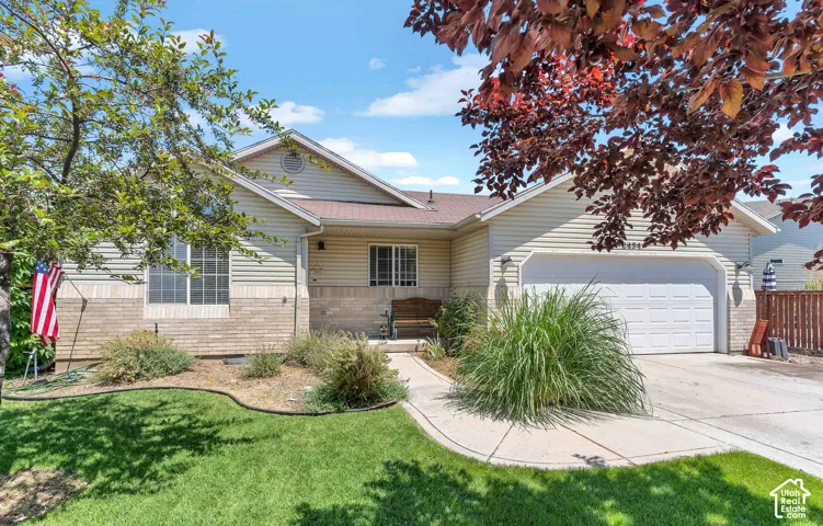 Exterior featuring horizontal siding, brick accents, a two-car garage, and mature landscaping