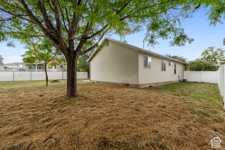 Expansive yard with mature trees, a fire pit, and white vinyl fencing