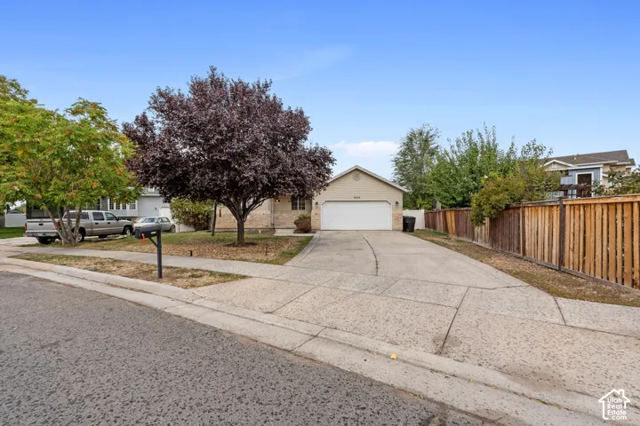 Single-story residence featuring a two-car garage, concrete driveway, and a wood privacy fence