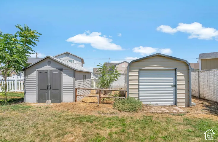 Two large storage sheds with 1 roll up door, chain link fencing, and a white picket fence