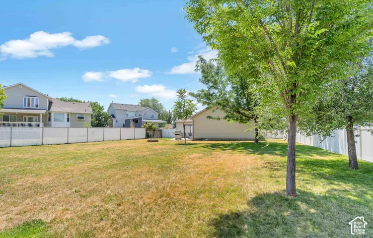 Expansive backyard featuring a partial vinyl fence and mature trees