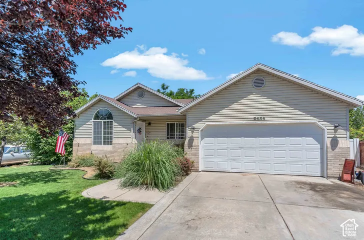 Exterior featuring light-toned siding, a two-car garage with a panel door, an arched window, and a concrete driveway