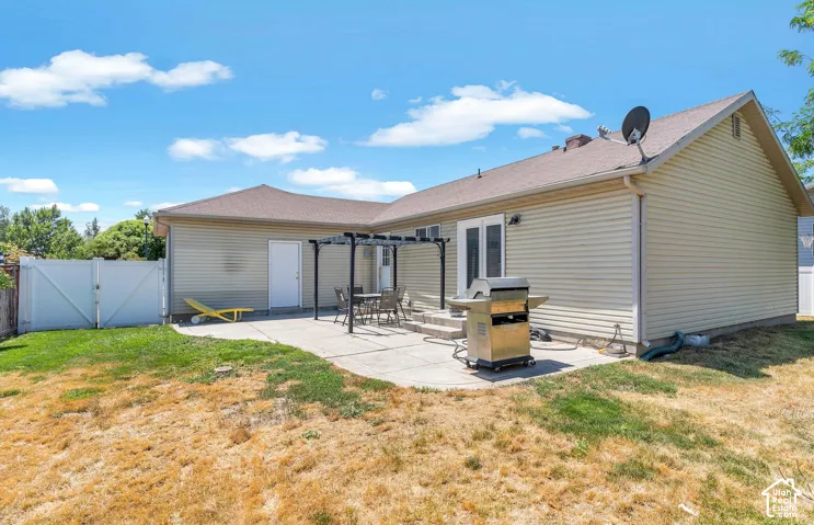 Rear patio featuring a pergola, concrete surface, and double exterior doors