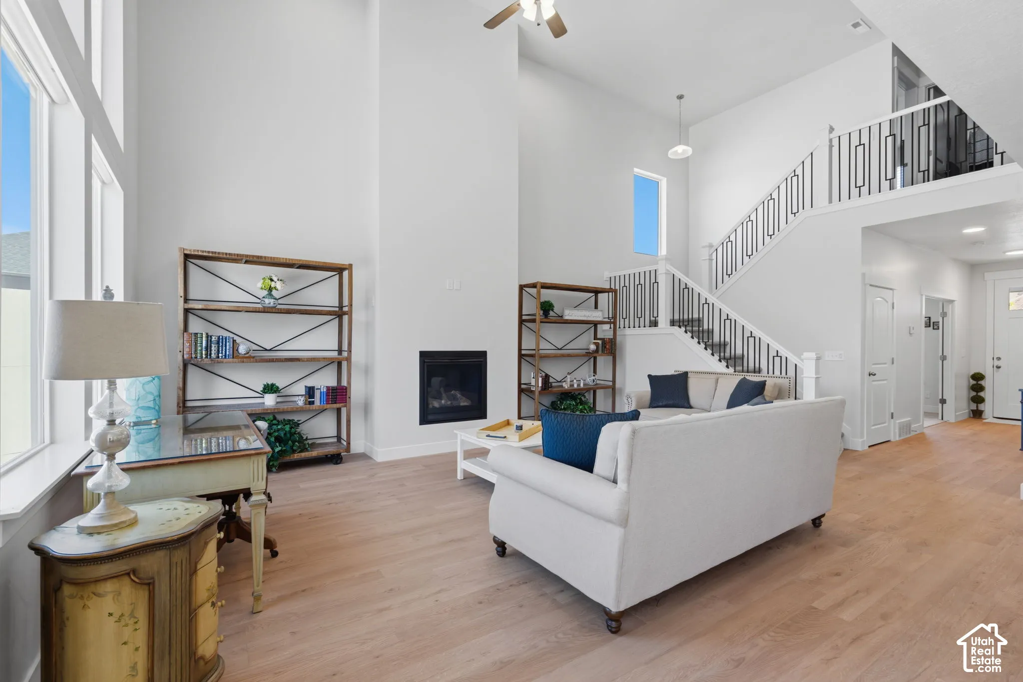 Vaulted ceilings with recessed lighting, an open staircase with wrought iron balusters, wood-finish flooring, and expansive windows.