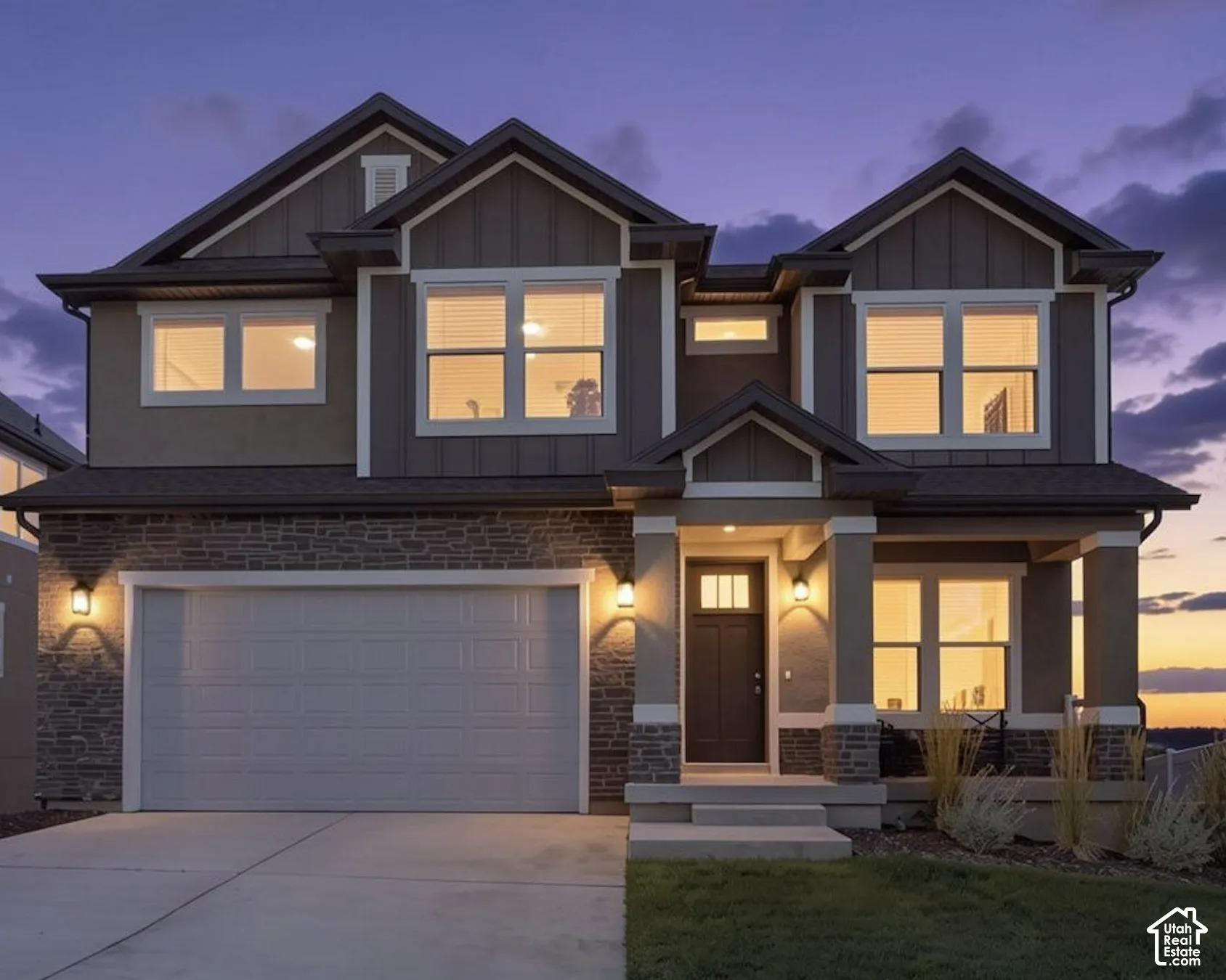 Two-story residence featuring a stone and siding exterior, an attached garage, a covered front porch with pillar supports, and multiple gabled rooflines.