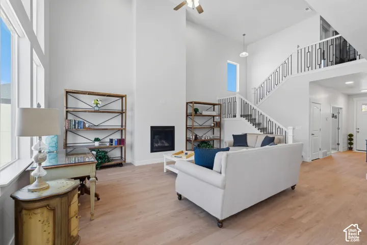 Vaulted ceilings with recessed lighting, an open staircase with wrought iron balusters, wood-finish flooring, and expansive windows.