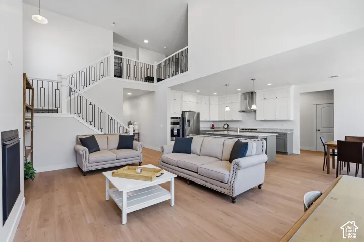 Open-concept living space featuring soaring ceilings, a mezzanine-level loft with metal railings, and abundant natural light from recessed ceiling fixtures.