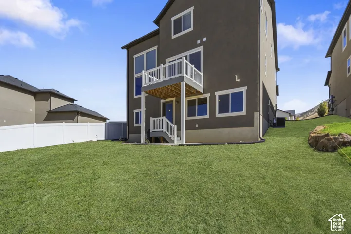 **AI GRASS**stucco exterior with multiple windows, second-story deck with white railing, ground-level patio door.