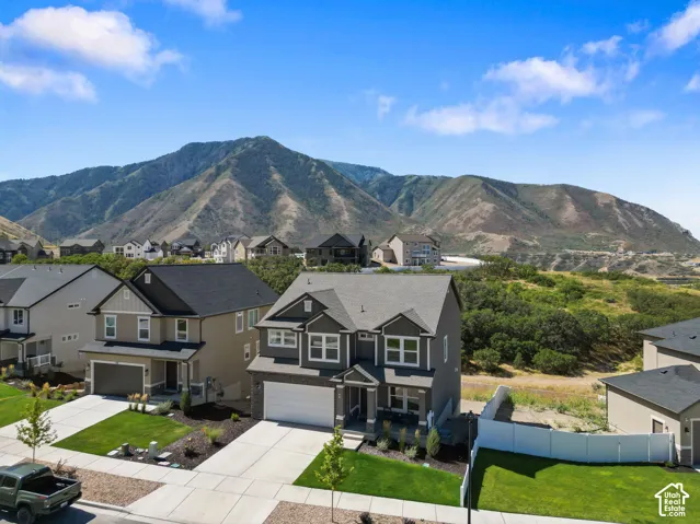 Two-story residence featuring a dark gray exterior with stone accents, a two-car garage, and a manicured front lawn.