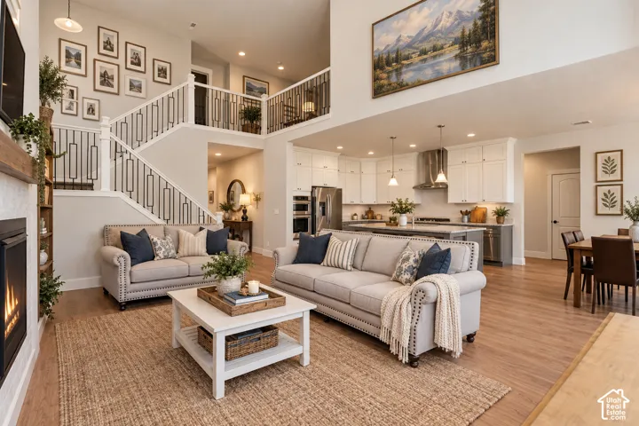 ENHANCED...Two-story living area with wood-finish flooring, a built-in fireplace, and a white and black iron staircase