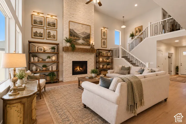 ENHANCED...Vaulted ceilings with recessed lighting, a stone-clad fireplace with a wood mantle, an open staircase with wrought iron balusters, wood-finish flooring, and expansive windows.