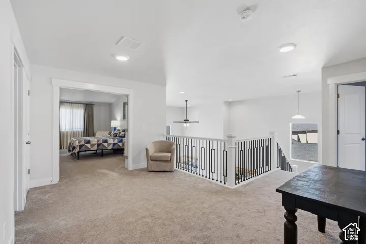 Loft area, Carpeted landing featuring white walls, recessed lighting, a decorative metal and wood railing, and a framed doorway entering the master bedroom.