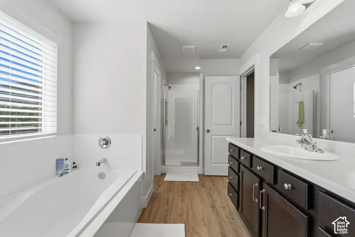 Spacious bathroom featuring an integrated soaking tub, vanity with ample storage, a large mirror, and a walk-in shower with a glass enclosure.