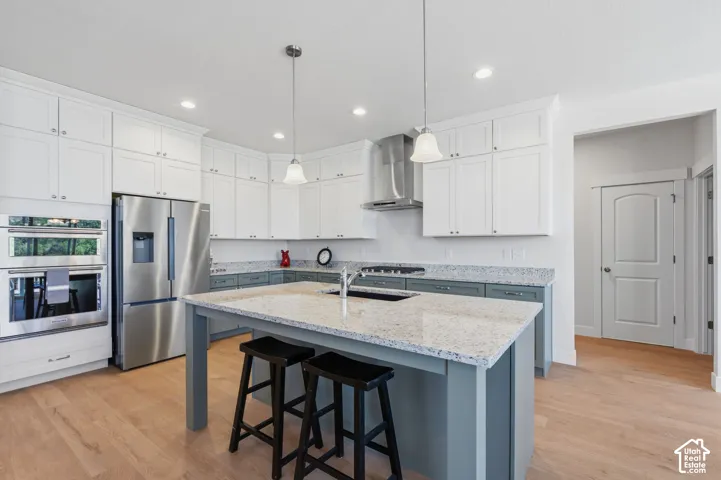 Modern kitchen featuring white cabinetry, stainless steel appliances, and a granite countertop island with seating for multiple diners.