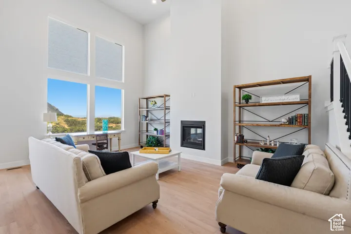 Bright open-concept living area showcasing soaring ceilings, large multi-pane windows framing natural light, and LPV flooring throughout.