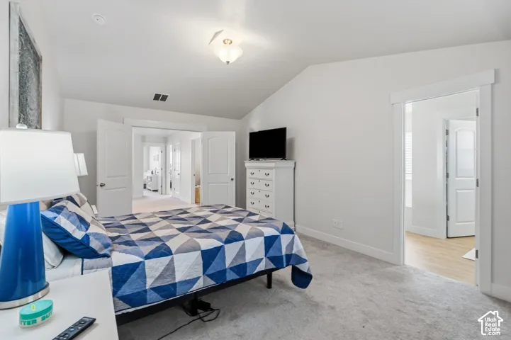 Master bedroom, vaulted ceiling, recessed lighting, white interior doors, carpet flooring.