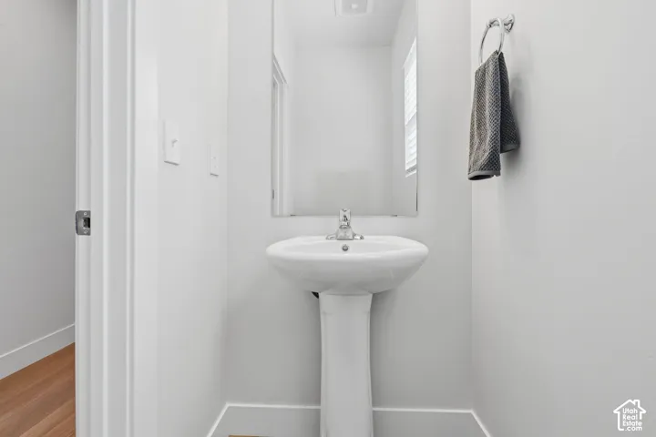 Pedestal sink with chrome faucet, framed wall mirror.