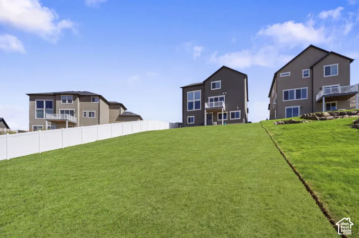**AI GRASS**expansive grassy slope with a white privacy fence.