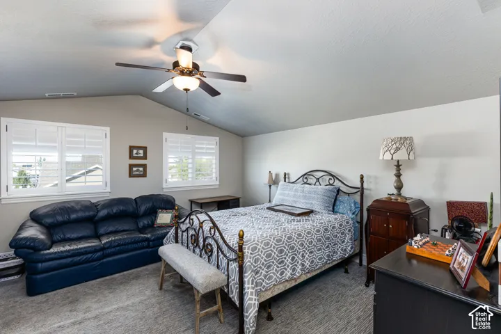 Angled ceiling with a ceiling fan, two windows with white plantation shutters, and light-toned walls