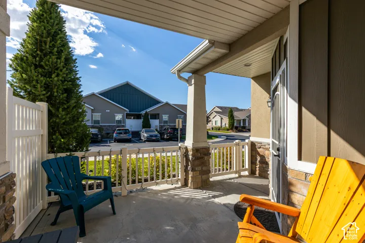 Covered porch featuring stone accents, white railing, and a durable concrete surface