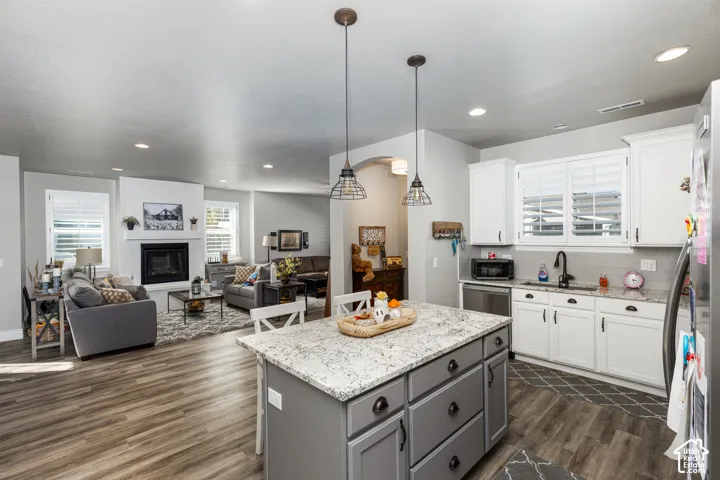 Kitchen island with a light-toned countertop, wood-finish flooring, recessed lighting, and white cabinetry