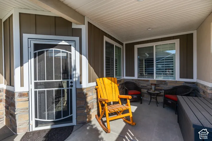 Covered front porch featuring a security screen door, stone veneer accents, and horizontal siding