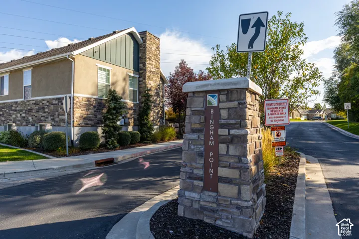 Stone-clad entry monument with signage, asphalt paving, and established landscaping