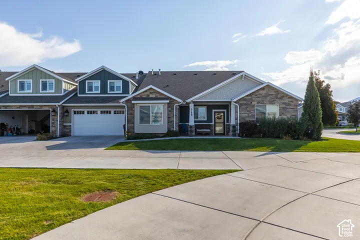 Multi-level exterior with dormer windows, stone accent siding, and an attached garage