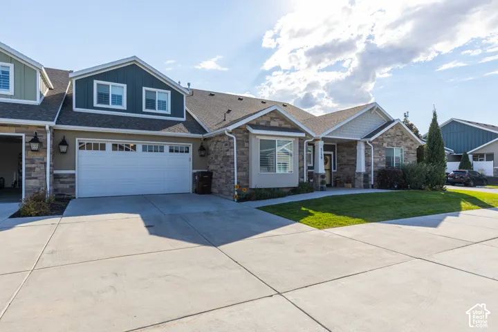 Stone veneer and siding exterior with a concrete driveway, attached two-car garage, and a manicured lawn