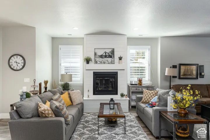 Fireplace with a shiplap surround, recessed lighting, and wood-finish flooring