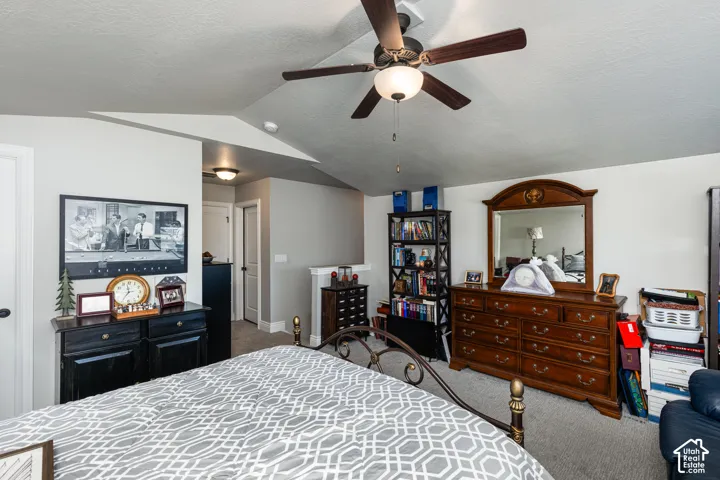 Vaulted ceiling with a ceiling fan light fixture, light gray walls, and light gray carpeted flooring