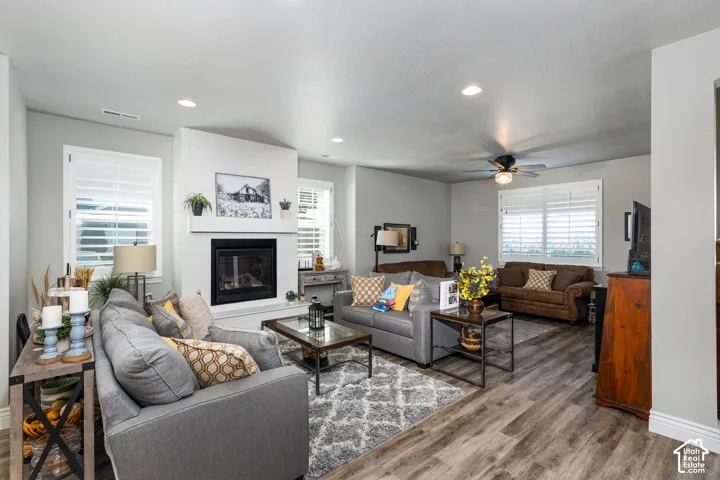 Living area featuring wood-finish flooring, a contemporary fireplace with a shiplap surround, recessed lighting, and white plantation shutters