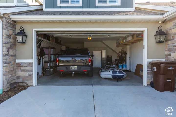 Attached garage with concrete flooring, overhead storage, and sconce lighting
