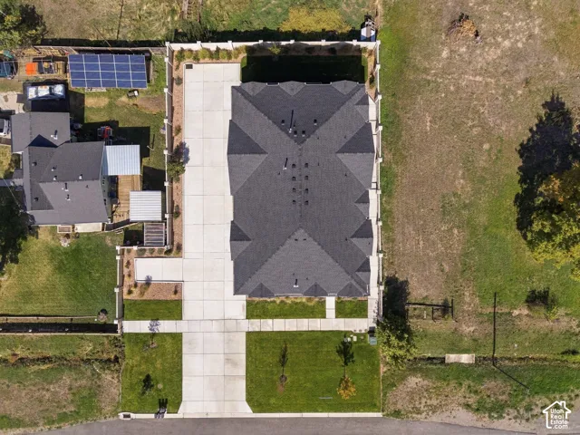 Expansive concrete driveway, dark shingle roofing, and a privacy fence