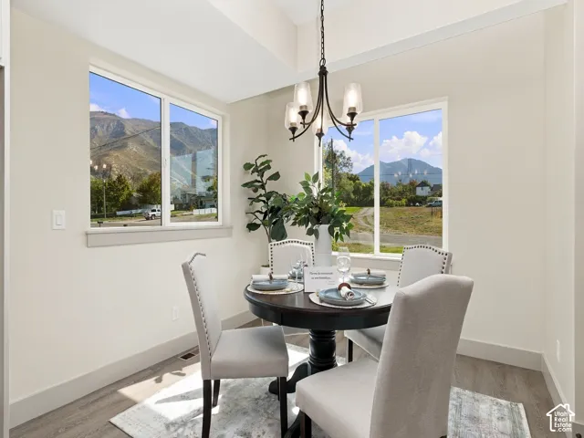 Wood-finish flooring, white painted walls, and an attached three-light chandelier