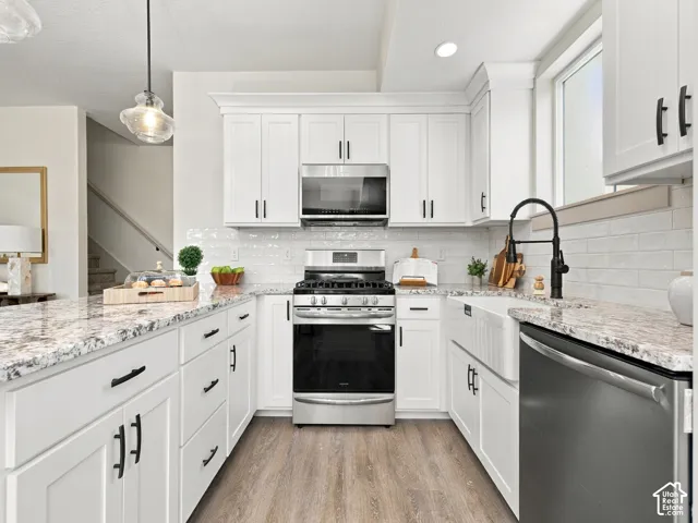 White shaker-style cabinetry, granite countertops, subway tile backsplash, stainless steel appliances, and a farmhouse sink with a matte black faucet