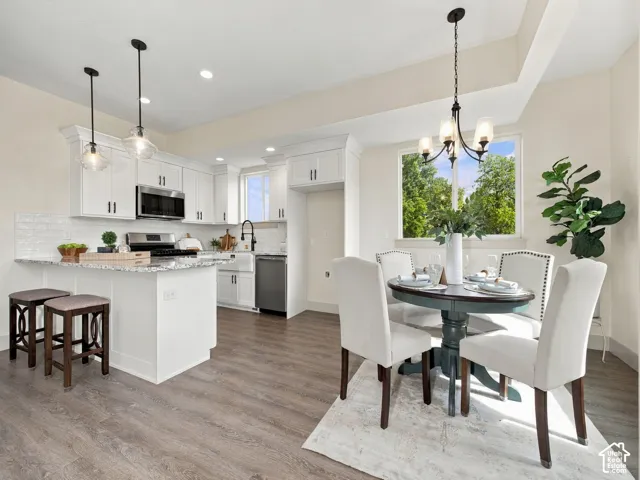 Kitchen featuring white cabinetry, stainless steel appliances, a white subway tile backsplash, and wood-finish flooring