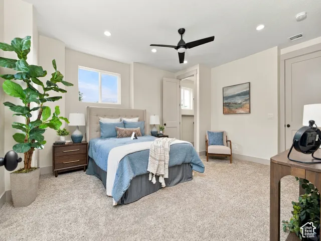 Recessed lighting illuminates the room, featuring a black ceiling fan and light-colored carpeting