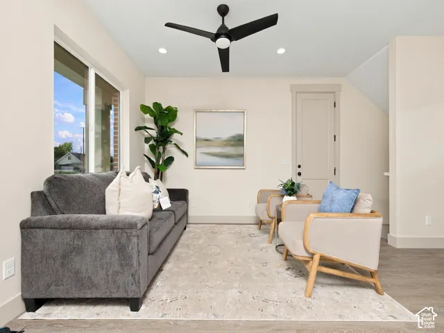 Large windows, recessed lighting, wood-finish flooring, a modern black ceiling fan, and a light-colored interior door