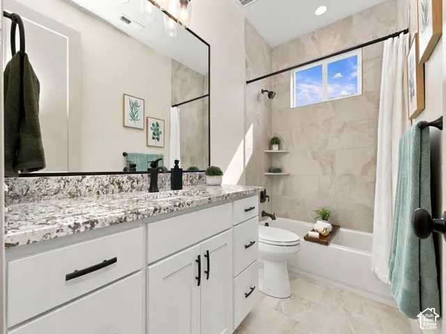 White cabinetry with dark hardware, stone countertop, integrated sink, and large rectangular mirror