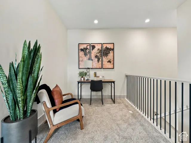 Carpeted loft area featuring recessed lighting, a desk, and a modern black spindle railing