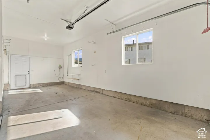 Concrete flooring, painted interior walls, two transom-style windows, and an overhead garage door mechanism