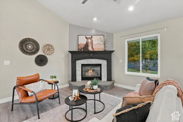 Sophisticated living room anchored by a gas fireplace with decorative tile surround and black mantel, complemented by recessed ceiling lighting and large transom windows overlooking landscaped grounds