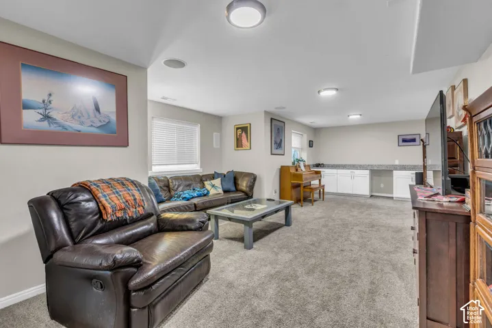 Plush carpet flooring, recessed ceiling lighting, built-in cabinetry with light-toned countertops, and a window with horizontal blinds