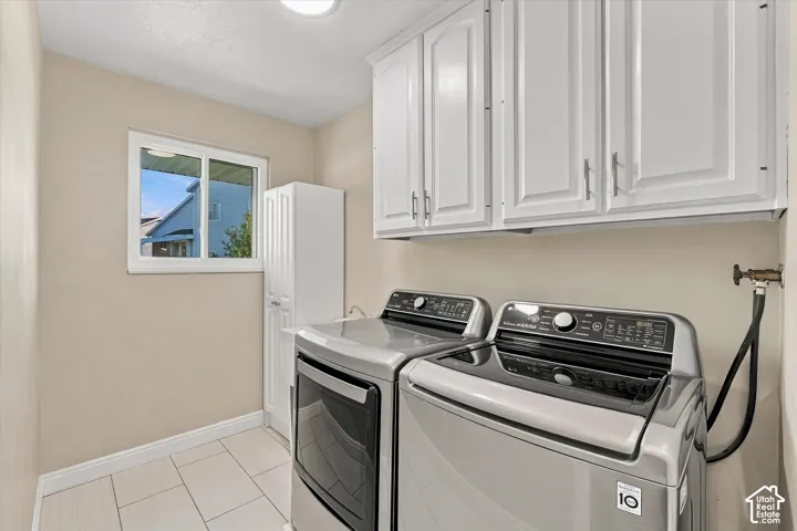 White upper cabinetry, white base cabinetry, light tile flooring, and a single window