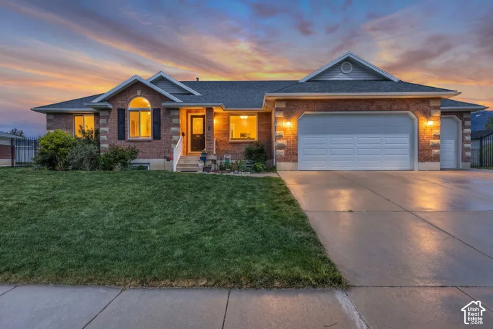 Brick exterior with stone accents, arched window, attached two-car garage, and concrete driveway