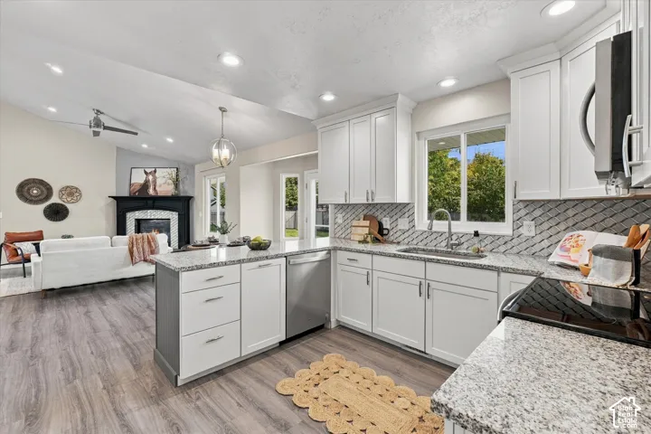 Open-concept living space with vaulted ceilings, wood-finish flooring, a kitchen island, and a built-in fireplace